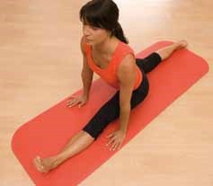 Eine Frau macht einen Spagat auf einer roten Yoga-Matte in einem hellen Raum