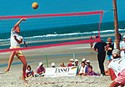 Spieler beim Strand-Volleyball, gelber Ball in der Luft, Zuschauer am Strand, Meer im Hintergrund