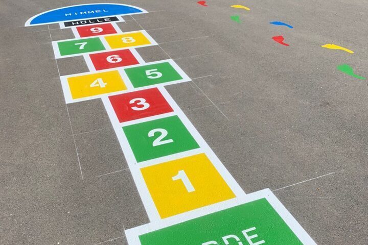 Bunte Himmel-und-Hölle-Spielgrafik auf einem Schulhof